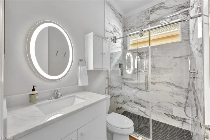 Bathroom with toilet, vanity, and a shower with door