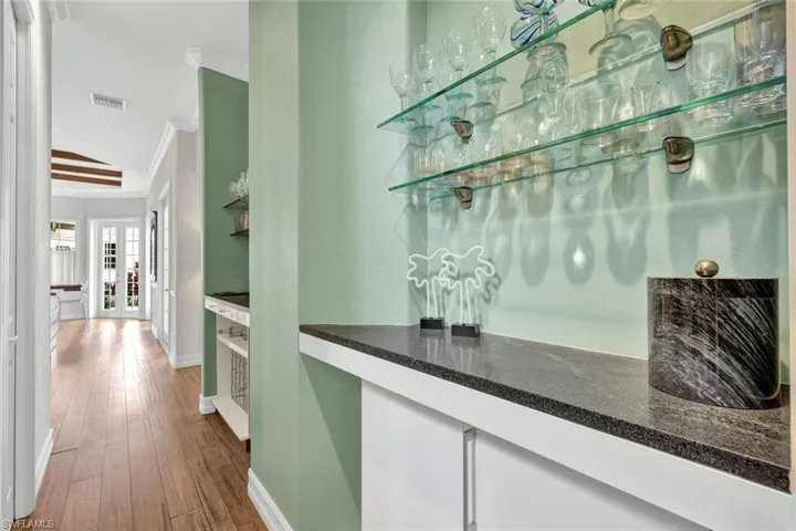 Bar featuring french doors, ornamental molding, vaulted ceiling, and wood-type flooring