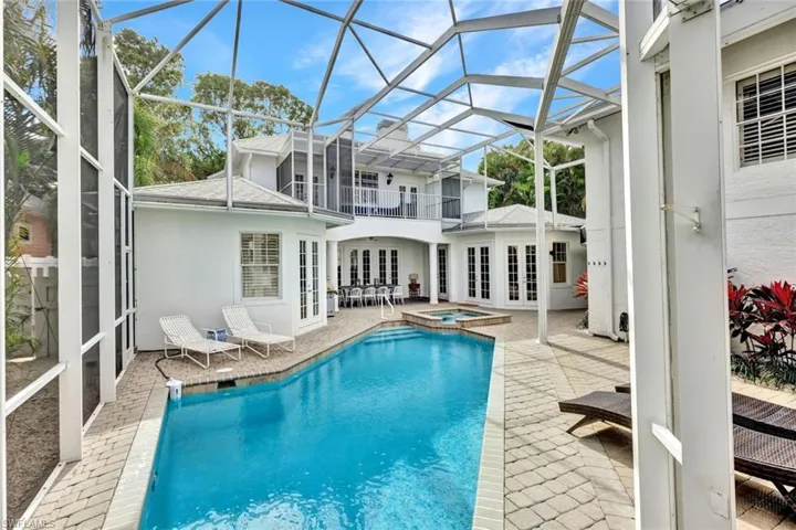 View of swimming pool featuring an in ground hot tub, a lanai, french doors, and a patio