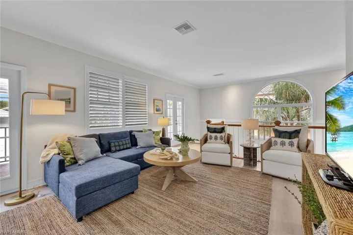 Living room with wood-type flooring, plenty of natural light, and ornamental molding