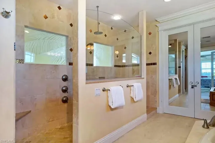 Bathroom featuring french doors, a walk in shower, and ornamental molding