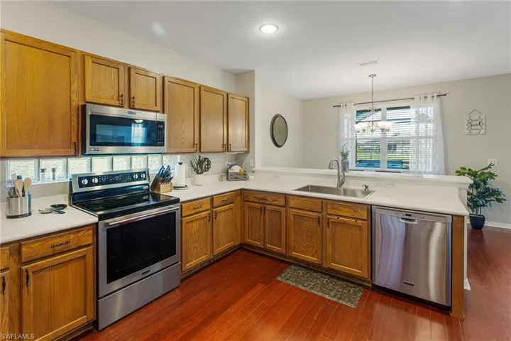 Kitchen featuring kitchen peninsula, appliances with stainless steel finishes, dark wood-type flooring, and sink