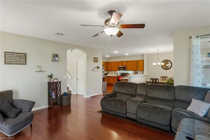 Living room with dark hardwood / wood-style flooring and ceiling fan with notable chandelier
