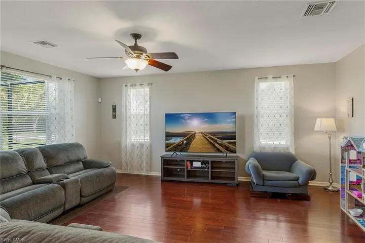 Living room with dark hardwood / wood-style flooring and ceiling fan