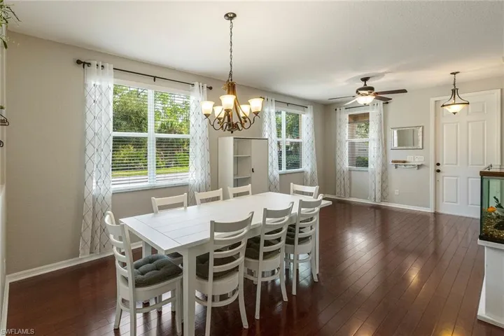 Dining space featuring ceiling fan with notable chandelier, dark hardwood / wood-style floors, and plenty of natural light
