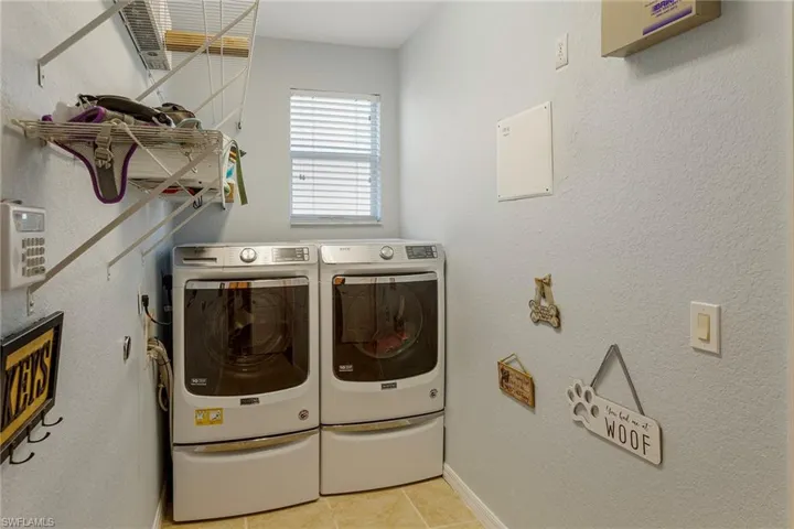 Laundry room featuring light tile patterned flooring and washing machine and clothes dryer