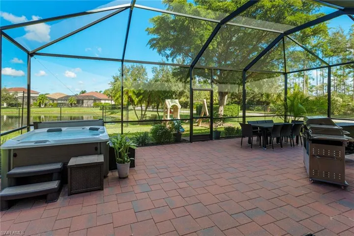 View of patio / terrace with a hot tub, glass enclosure, and grilling area