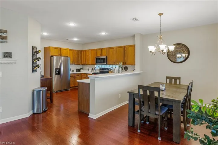 Kitchen with dark hardwood / wood-style flooring, kitchen peninsula, hanging light fixtures, a notable chandelier, and appliances with stainless steel finishes
