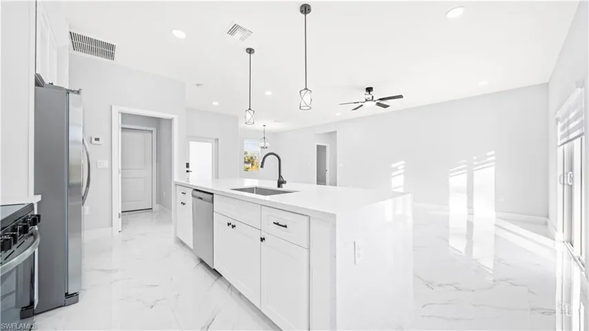 Kitchen with white cabinets, light marble finish floors, stainless steel appliances, light stone countertops, and recessed lighting