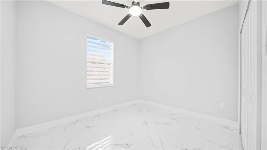 Empty room with marble finish floors and a ceiling fan