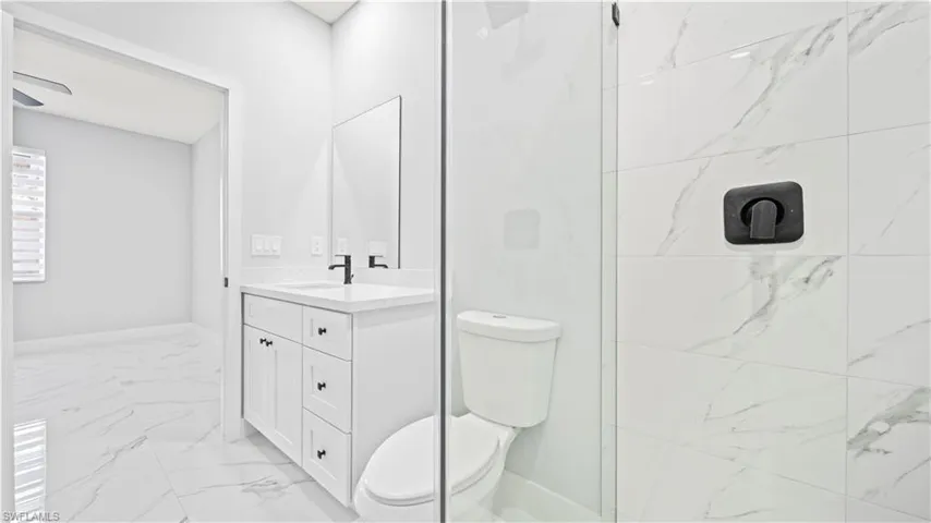 Bathroom with light marble finish floors, vanity, and a shower