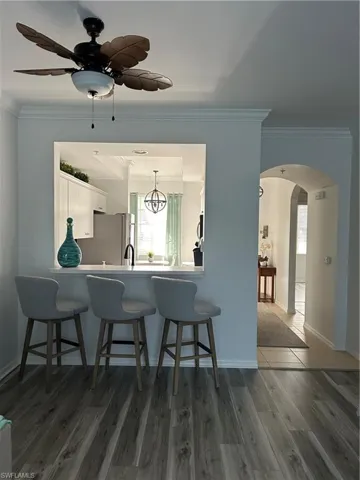 Kitchen with new ceiling fans throughout with notable chandelier, a healthy amount of sunlight, white cabinetry, and dark wood-type flooring