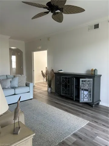 Living room featuring ceiling fan, hardwood / wood-style flooring, and ornamental molding