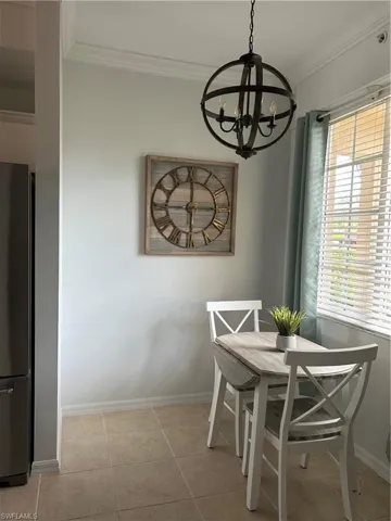 Tiled dining area featuring a healthy amount of sunlight, crown molding, and a chandelier