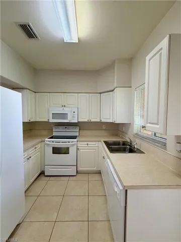 U-shaped kitchen featuring white cabinetry, light-toned countertops, and tiled flooring