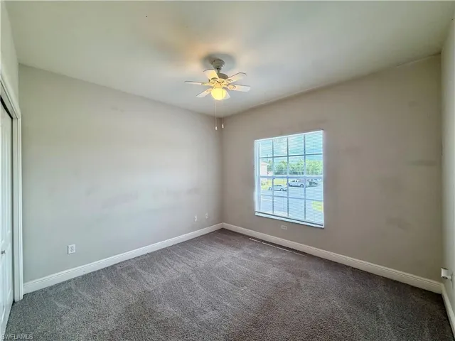 Carpeted room featuring a ceiling fan with integrated lighting, a window with horizontal muntins, and a bi-fold closet door