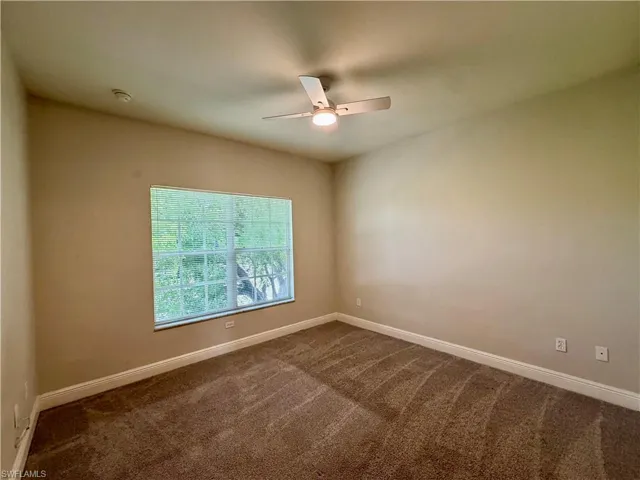 Room featuring neutral-toned walls, brown patterned carpeting, and white baseboards