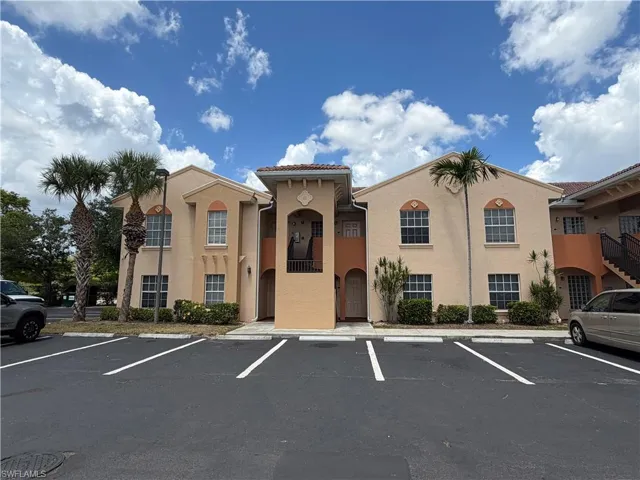 Multi-level building with a stucco exterior, arched window accents, and a tile roof