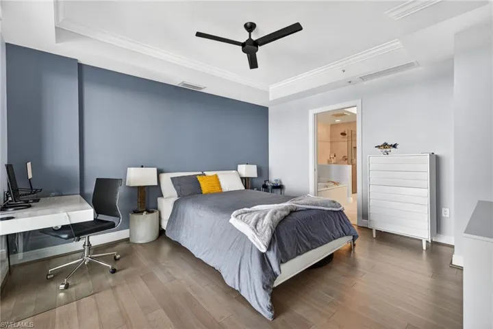 Bedroom with a raised ceiling, wood-type flooring, ceiling fan, and ornamental molding