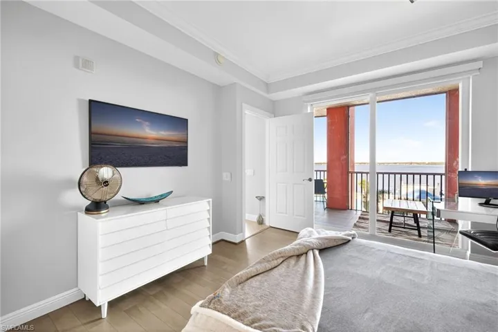 Bedroom with wood finished floors, access to exterior, and ornamental molding