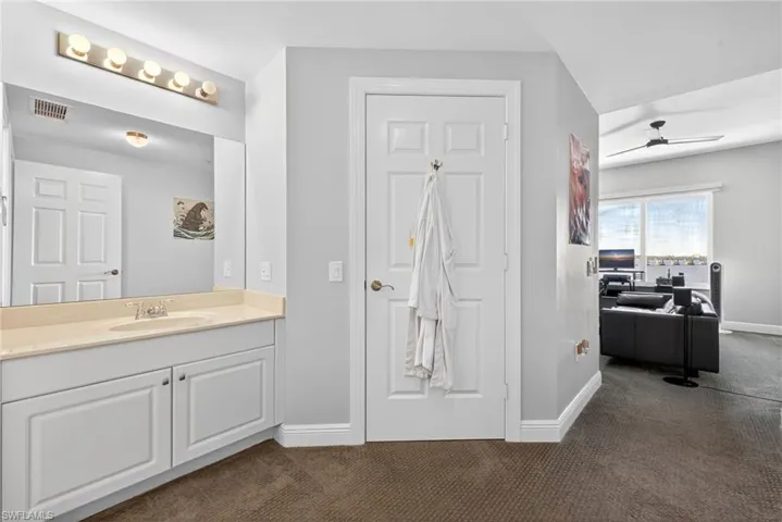 Bathroom with dark carpet, vanity, and ceiling fan