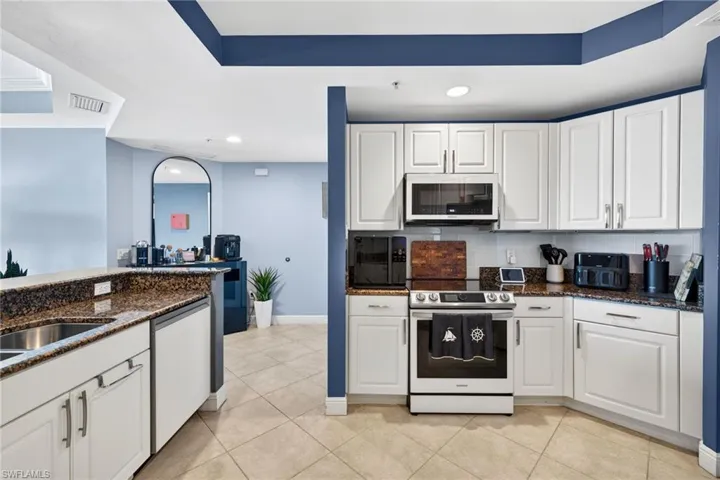 Kitchen with white cabinetry, stainless steel range with electric cooktop, dark stone countertops, recessed lighting, and white dishwasher