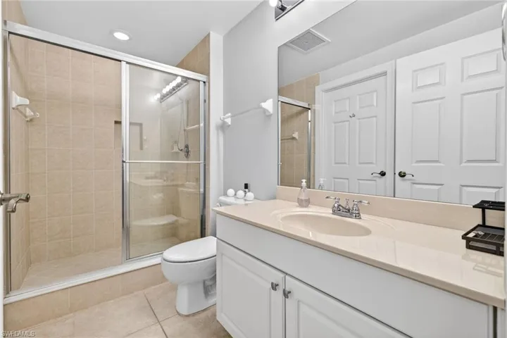 Bathroom featuring vanity, a shower stall, light tile patterned floors, and recessed lighting