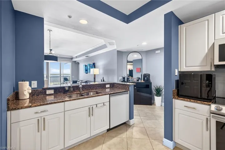 Kitchen featuring dark stone counters, white cabinetry, a tray ceiling, and recessed lighting