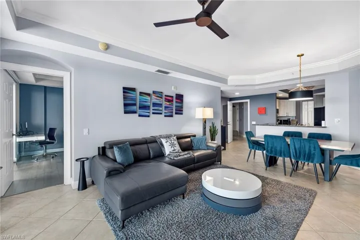 Living room with a raised ceiling, an office area, ornamental molding, recessed lighting, and light tile patterned floors