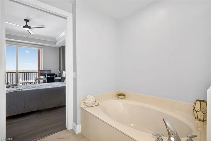 Ensuite bathroom with ceiling fan, a garden tub, and ornamental molding
