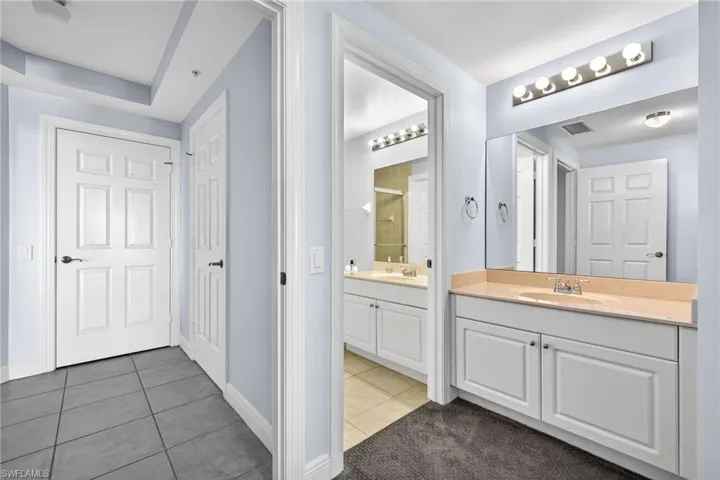 Bathroom with two vanities, dark tile patterned floors, and a shower
