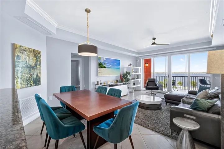 Dining area featuring ceiling fan, ornamental molding, light tile patterned flooring, and a raised ceiling