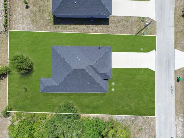 Manicured lawn surrounding the property, featuring a durable shingle roof and a concrete driveway