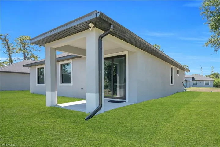 Rear exterior showcasing a covered patio with a concrete slab