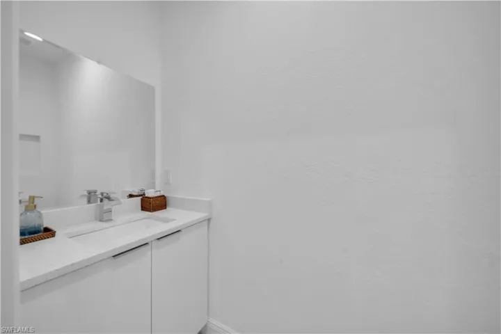 Contemporary vanity featuring a rectangular under-mount sink, chrome faucet, and integrated white countertop