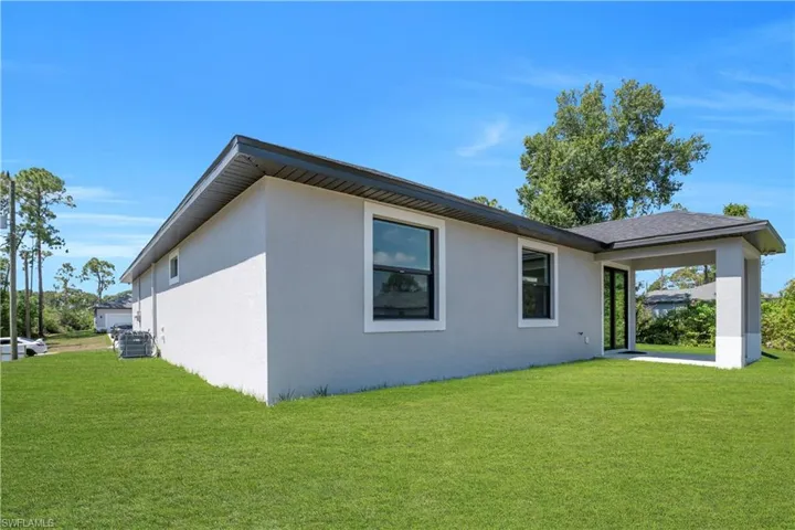 Expansive green lawn bordering the light gray stucco exterior
