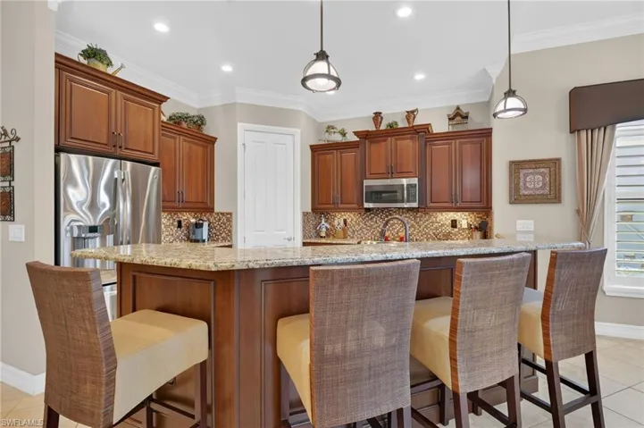 Kitchen with tasteful backsplash, light stone counters, light tile patterned floors, decorative light fixtures, and recessed lighting