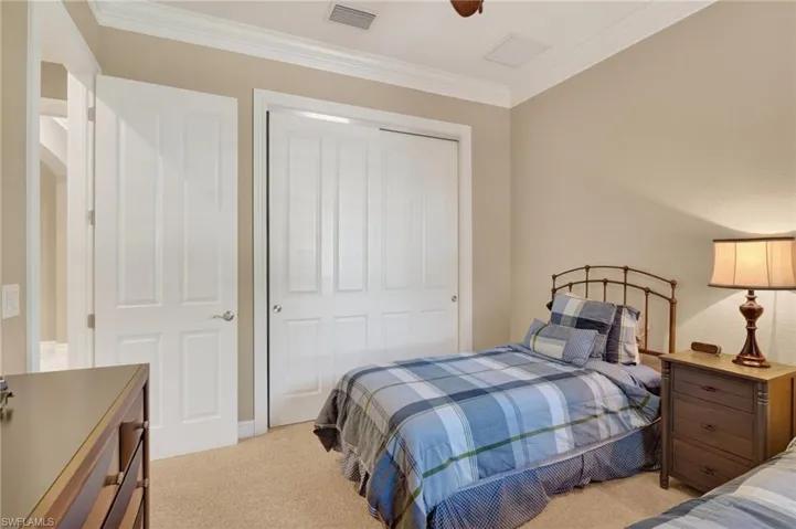 Bedroom featuring ornamental molding, light colored carpet, a closet, and a ceiling fan
