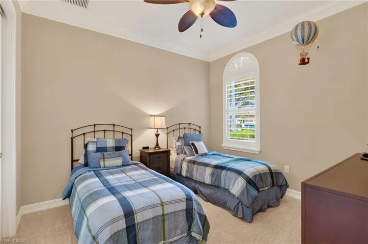 Bedroom with light colored carpet, crown molding, and a ceiling fan