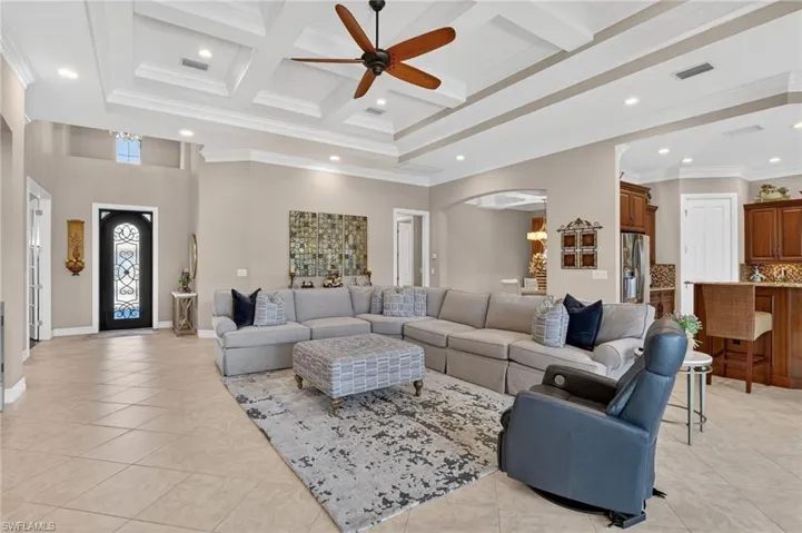 Living room featuring ornamental molding, arched walkways, coffered ceiling, recessed lighting, and a towering ceiling