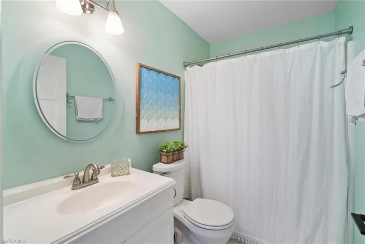 Bathroom with vanity, a shower with curtain, and toilet