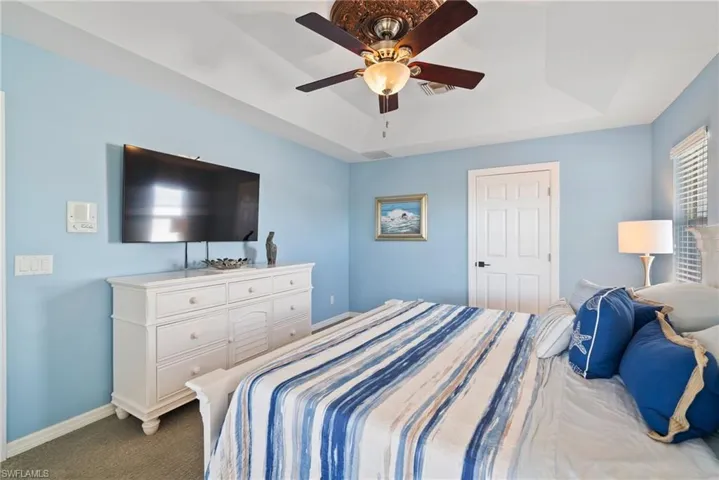 Bedroom with a tray ceiling, ceiling fan, and carpet