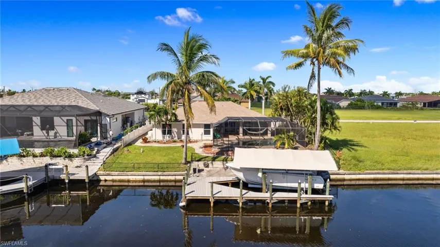 View of dock with a lawn, a water view, and glass enclosure