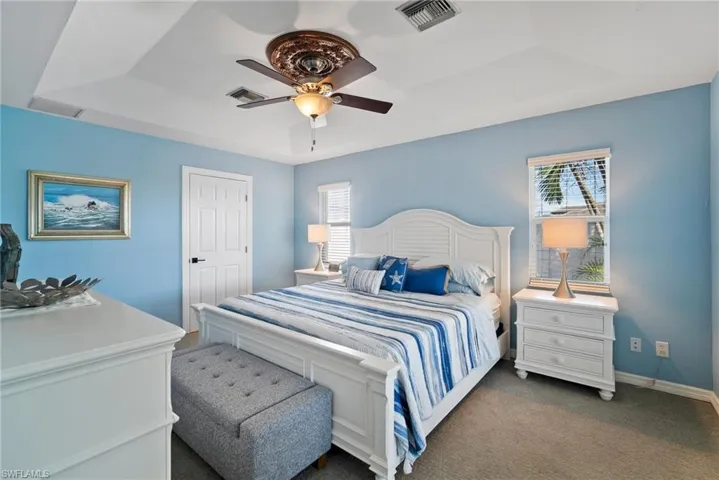 Bedroom featuring ceiling fan, a raised ceiling, and carpet floors