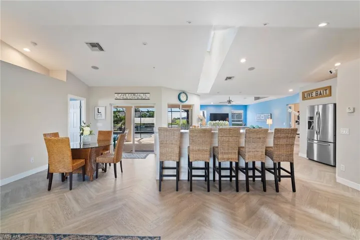 Kitchen with a kitchen bar, a kitchen island, light parquet flooring, and stainless steel refrigerator with ice dispenser