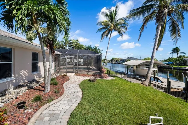 View of yard featuring a dock, a water view, and glass enclosure