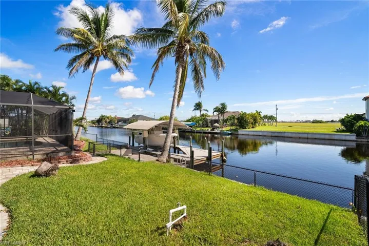 View of dock with a yard, glass enclosure, and a water view