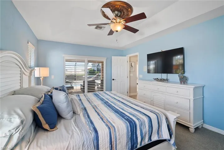 Bedroom with ceiling fan, dark carpet, and a tray ceiling