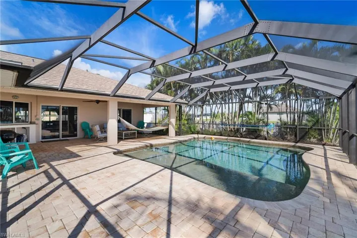View of swimming pool featuring ceiling fan, a patio area, and glass enclosure