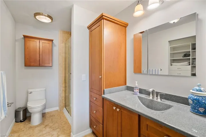 Bathroom featuring walk in shower, vanity, and toilet